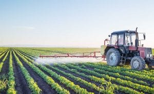 Distant shot of tractor spraying liquid onto crops